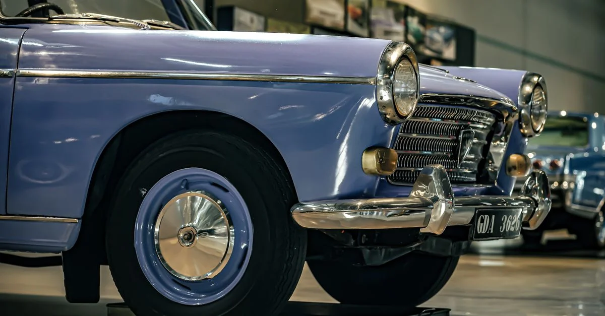 Gros plan sur une voiture ancienne classique, mettant l'accent sur la roue avant et le phare, exposée lors d'un salon automobile à Mysuru.